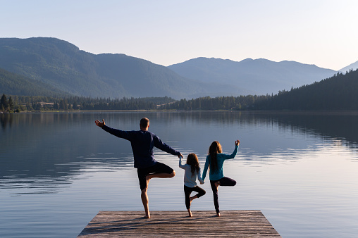 Family practising yoga outdoors. Healthy lifestyle spending time outdoors.