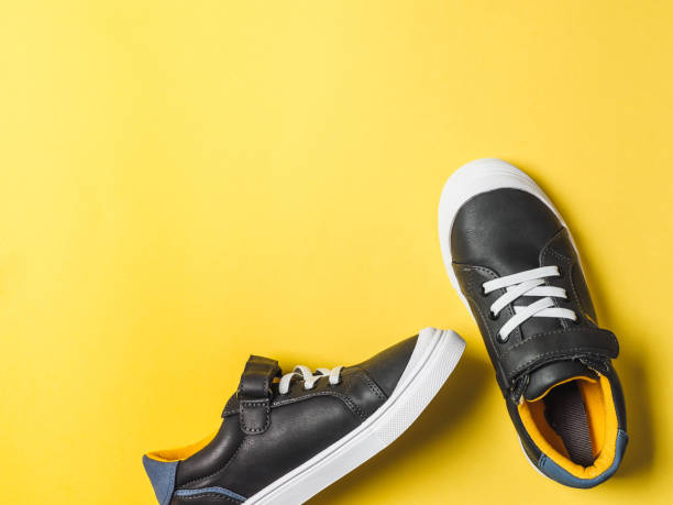 istock Gray and yellow sneakers on yellow background 1163781359