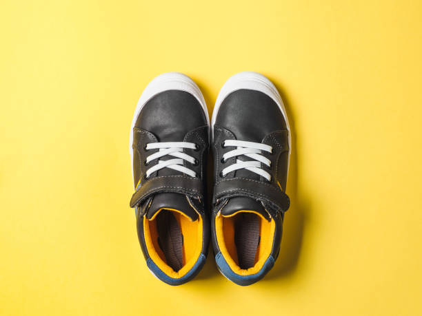 istock Gray and yellow sneakers on yellow background 1163781372