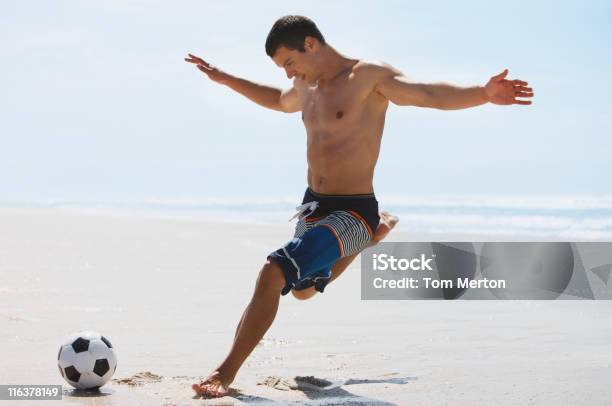 Foto de Homem Chute A Bola De Futebol Na Praia e mais fotos de stock de Futebol - Futebol, Praia, Cabelo Castanho