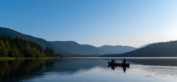 POv view of woman paddling on red inflatable canoe on peaceful environment in Norway. Blue lake and green mountains