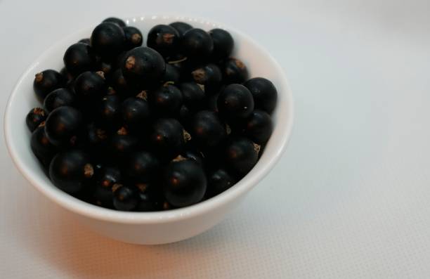 istock Ripe black currant berries in a small white Cup on a white background. Black currant harvest. Natural vitamin. Healthy food. vegetarian food. 1163781990
