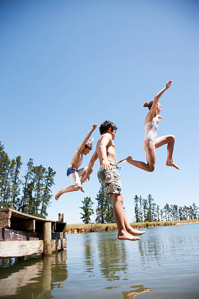 crianças pulando no lago - vitality innocence clothing human age - fotografias e filmes do acervo