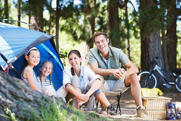 famille assis à l'extérieur de tente de camping - camping family tent couple photos et images de collection