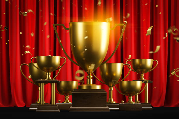 istock Golden champion trophies and confetti on red 1163784127