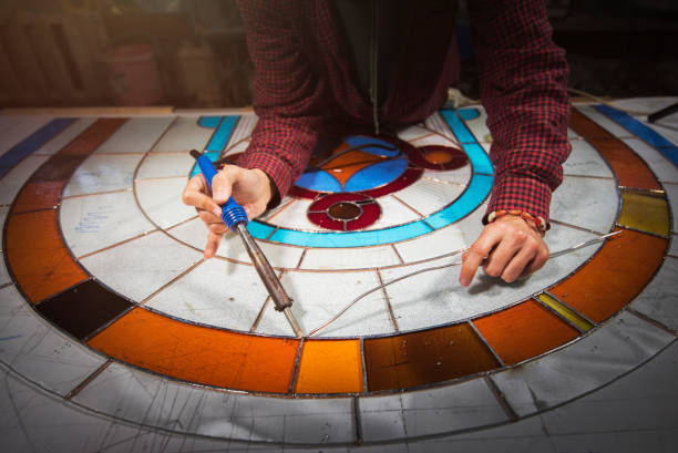 istock Unrecognizable male hands working on stained glass project, soldering with tin 1163785855