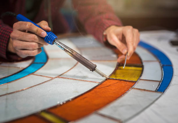 istock Unrecognizable male hands working on stained glass project, soldering with tin 1163785951
