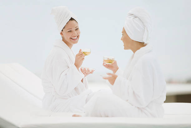 mujeres en una bata de baño mientras disfruta de un té junto a la piscina del spa - bathrobe women cup towel fotografías e imágenes de stock