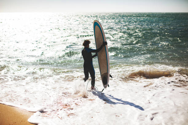 istock Man with surfboard at the beach 1163787135