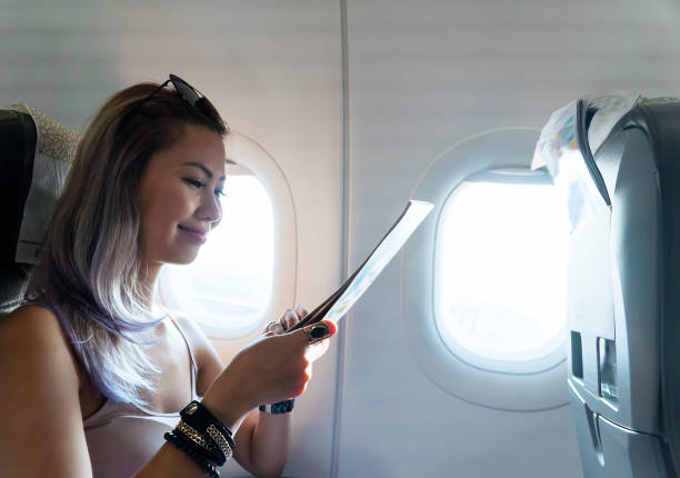 istock Woman reading magazine in airplane 1163788030