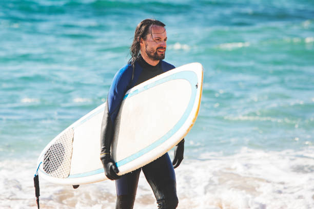 istock Man with surfboard at the beach 1163788524