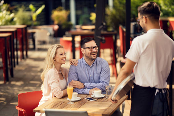 istock Happy couple communicating with waiter in a cafe, 1163788717