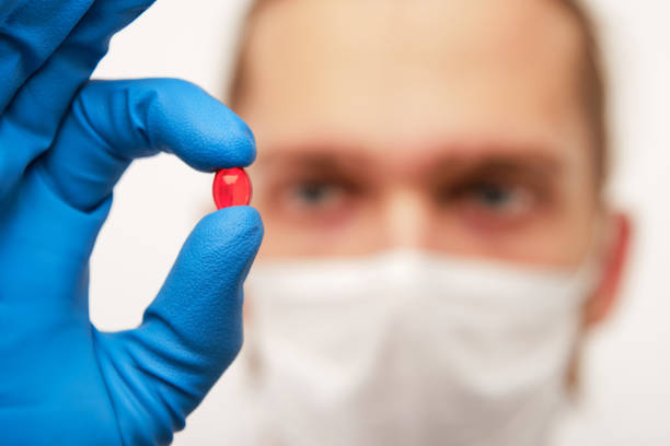 istock Pharmacist holding small red pill in hand 1163789602