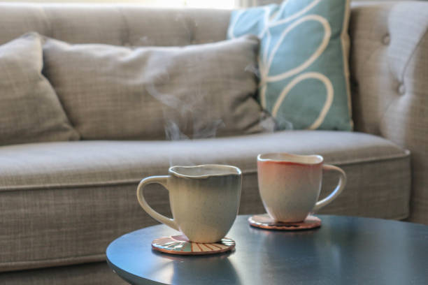 istock Close up of hot drinks with steam on a table in front of a sofa 1163789631