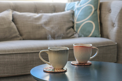 Close up of hot drinks with steam on a table in front of a sofa