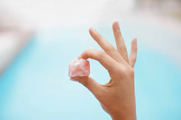 Photo of Hand holding crystal at poolside