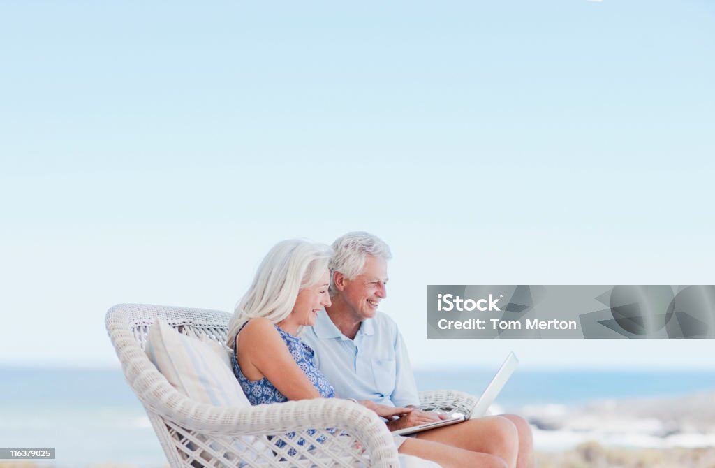 Couple à l'aide d'un ordinateur portable sur la plage Terrasse - Photo de Ordinateur portable libre de droits