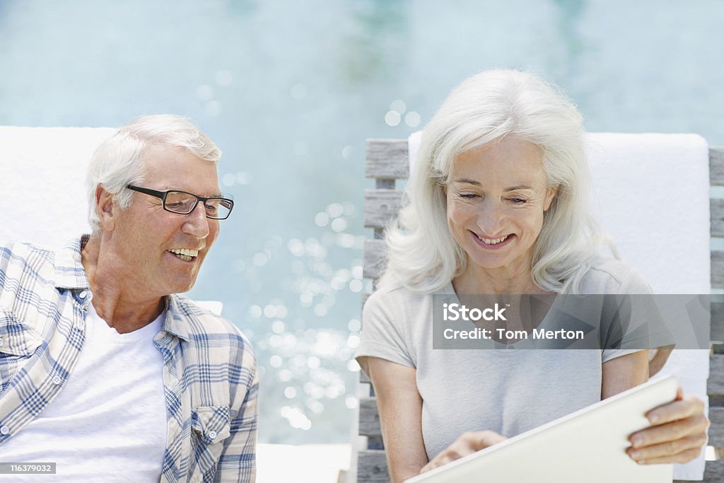 Пожилая пара с помощью ноутбука на бассейн - Стоковые фото Бассейн роялти-фри