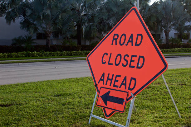 istock Road closed ahead with left facing arrow, on metal a-frame stand 1163791907