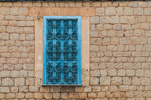 Turquoise window shutters with heart-shaped window grating in a brick wall facade in Valldemossa, Majorca, Spain - head-on view, landscape format, copy space