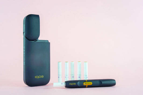 nuova sigaretta elettronica iqos (sistema di riscaldamento tabacco) su sfondi rosa. - tobacco sticks foto e immagini stock