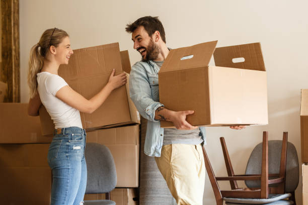 Young couple carrying big cardboard box into new home.Moving house. stock photo