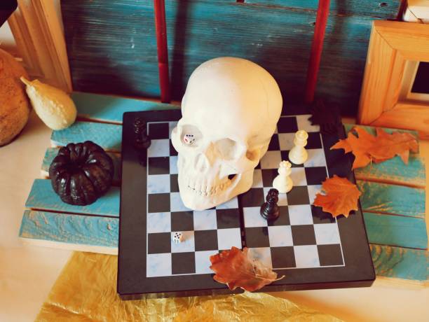 istock Decorative composition of a skull, pumpkins, frames and mystical decor on a chessboard with figures 1163799638