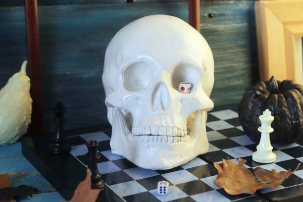 istock Decorative composition of a skull, pumpkins, frames and mystical decor on a chessboard with figures 1163799655