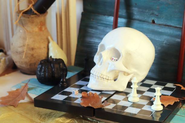 istock Decorative composition of a skull, pumpkins, frames and mystical decor on a chessboard with figures 1163799659