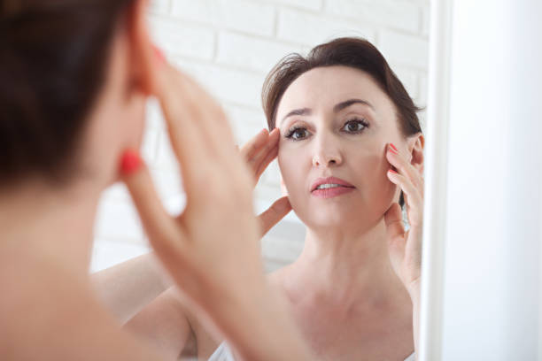 istock Woman looking at wrinkles in mirror. Plastic surgery and collage 1163799870