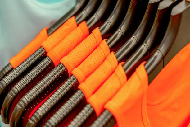 orange sports clothing on hangers in a shop, abstract background