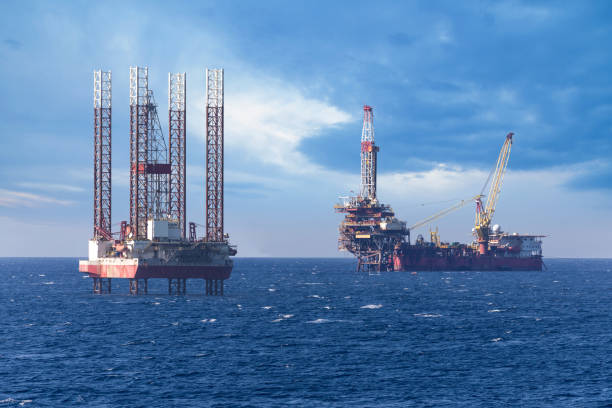 istock Big offshore oil rig drilling platform complex with anchored ship 1163808474