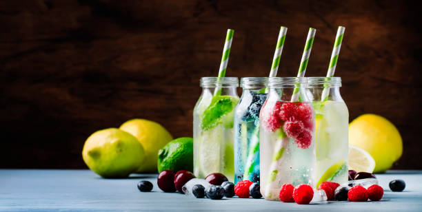 summer drinks set. berry, fruit and citrus non-alcoholic refreshing ice cold beverages and cocktails in glass bottles on blue background - healthy drink imagens e fotografias de stock