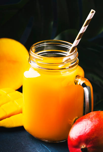 istock Mango juice or cocktail in glass jar with fresh fruit on blue tropical background, copy space, selective focus 1163813964