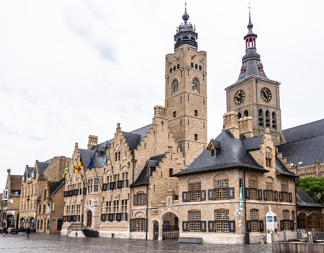 Diksmuide, Flanders, Belgium -  June 19, 2019: Grote Markt. Brown brick historic City Hall, or Stadhuis, building under gray sky. Rain Wet market square. Saint Nicolas church clock tower in back.