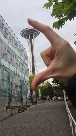 Seattle, Washington, United States - April 21, 2015:  Amusing tourist photo, with perspective, appearing to show the fingers of a man crushing the Space Needle in Seattle, Washington, April 21, 2015