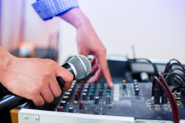 istock Microphone in hand and adjust an audio mixer controller in the control room, Sound mixer control for live music and studio equipment 1163817436