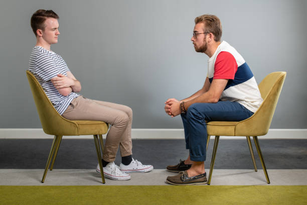 терапия сессии между двумя молодыми мужчинами - talking chair two people sitting стоковые фото и изображения