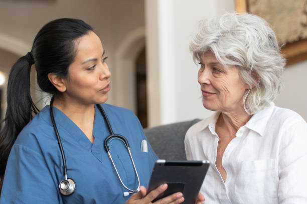 врач-женщина с помощью планшета со старшим пациентом - doctor digital display digital tablet healthcare and medicine стоковые фото и изображения