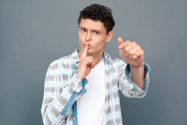 istock Man isolated on gray wall free style standing finger on lips silence 1163828039