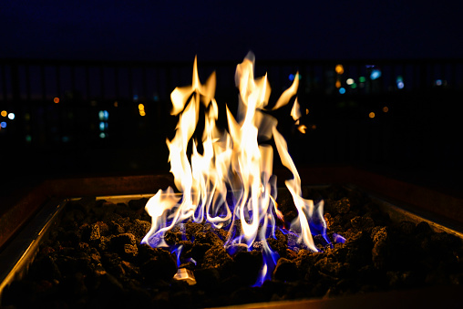 Flames in a Gas Fire Pit on Rooftop with City Bokeh