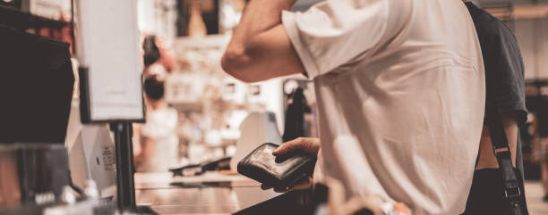 consommateur adulte payant avec carte de crédit dans le magasin, tenant un portefeuille - supermarket cash register checkout counter credit card photos et images de collection