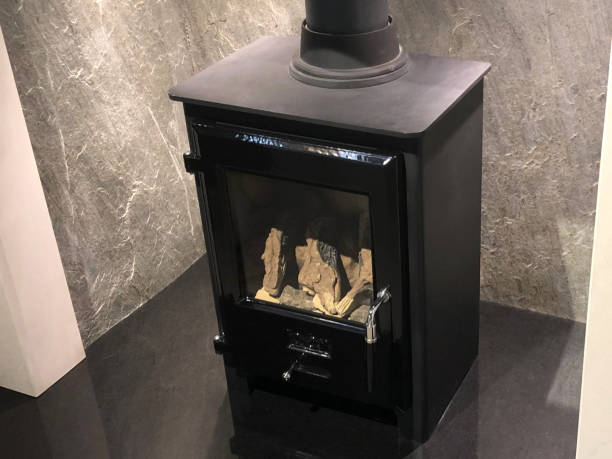 image of square cast iron woodburner / contemporary log wood burning stove fireplace mantle for fire flames to burn and generate heat to warm up room instead of gas boiler central heating, modern multifuel stove wood burner stand and chimney flue - flue gas imagens e fotografias de stock