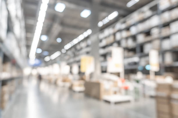 l'industria del magazzino sfuma lo sfondo con il magazzino all'ingrosso logistico, la sfocata navata interna del silo industriale per l'inventario della merce per mobili e il materiale in legno, le forniture per l'edilizia grande magazzino - department store immagine foto e immagini stock