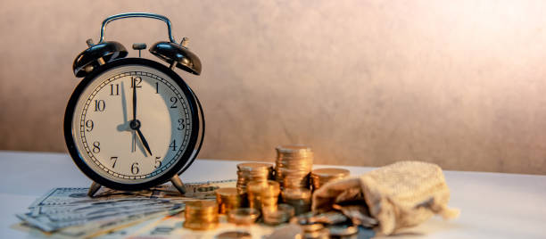 orologio e pila di monete sul tavolo. investimento nel tempo - making money gold euro symbol time foto e immagini stock