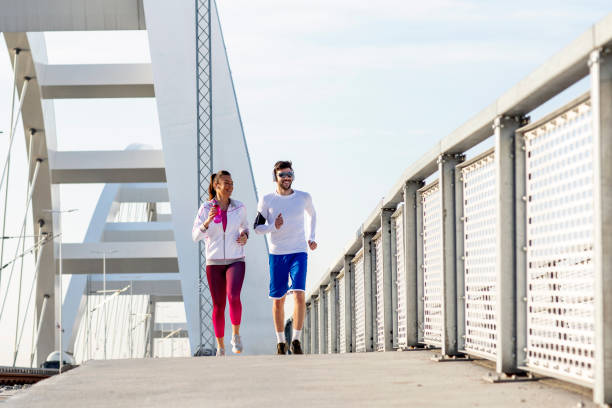 istock Couple jogging at the bridge with headphones 1163858794
