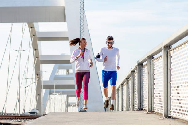 istock Couple jogging at the bridge with headphones 1163858796
