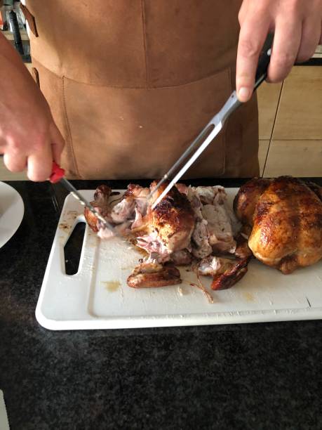 carving roast chicken chopping up rotisserie chicken on a kettle grill smoking meat rotisserie barbecue grill stock pictures, royalty-free photos & images