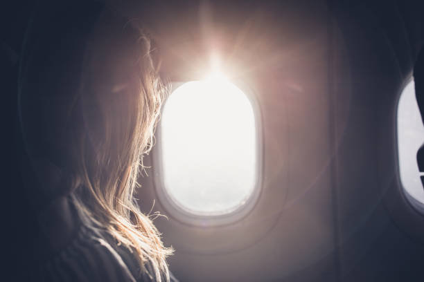 Looking through airplane window! Young woman traveling by airplane and looking through window. passenger cabin photos stock pictures, royalty-free photos & images
