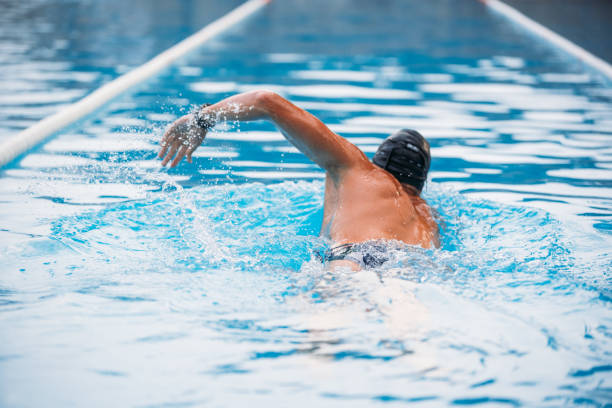 istock Athletic Young man swimming the back crawl in a pool. Swimming competition. 1163863108